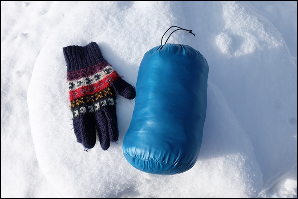 Daunenjacke im Beutel - mit Handschuh zum Größenvergleich