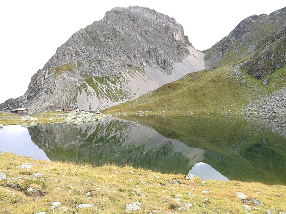 Spiegel-Bild. Kleine Hütte unter großen Felsen am Obstanser See | Karnischer Höhenweg, Osttirol