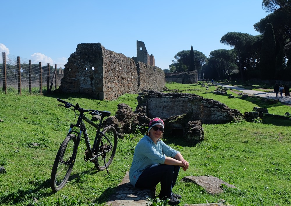 Mit dem Fahrrad auf der Via Appia Antica, Frau mit Fahrrad und Ruine